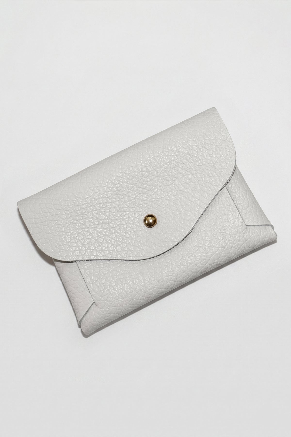 White textured leather pouch with curved flap closure and gold snap button.