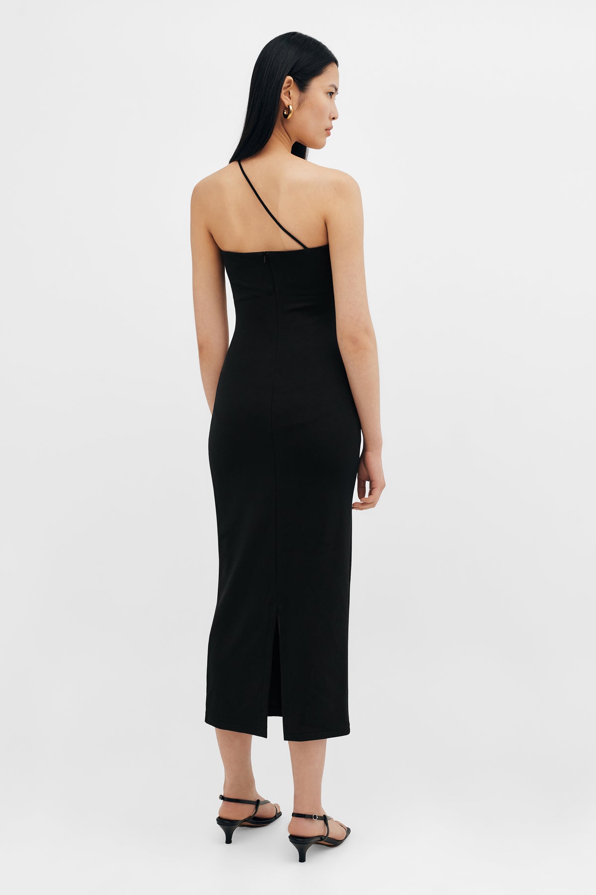 Black sleeveless midi dress with thin straps and front slit, worn with black kitten heel sandals.