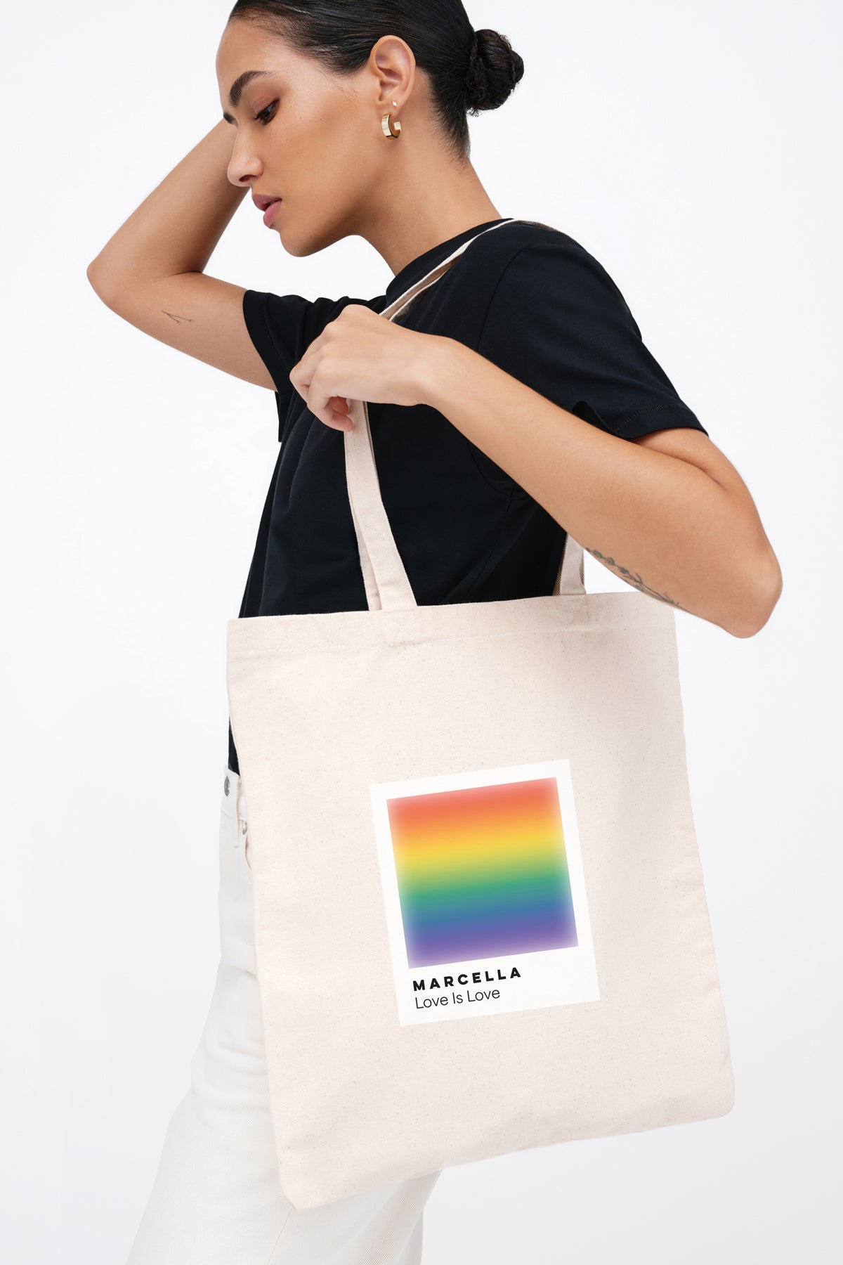 Natural canvas tote bag with rainbow gradient square and "Marcella Love is Love" text design.